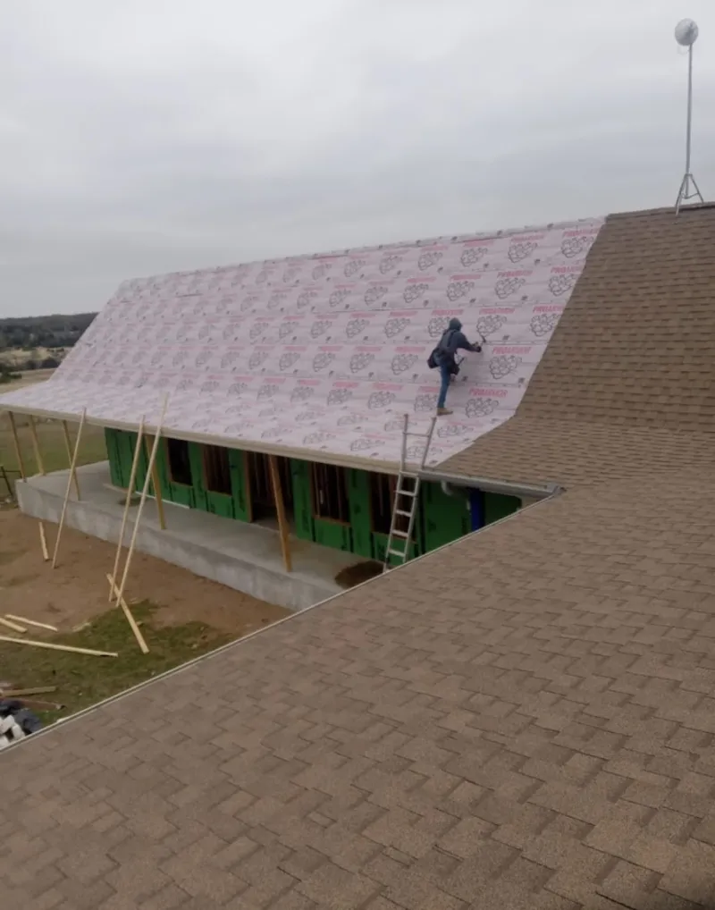 Worker preparing underlayment for a metal roof installation in Ridgeway